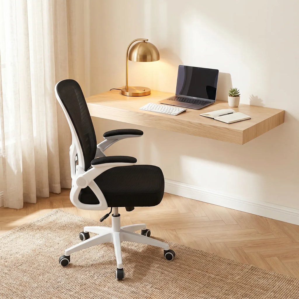 Chaise ergonomique District 12 mesh noire et blanche devant bureau flottant en bois clair avec lampe or et ordinateur, lumière naturelle