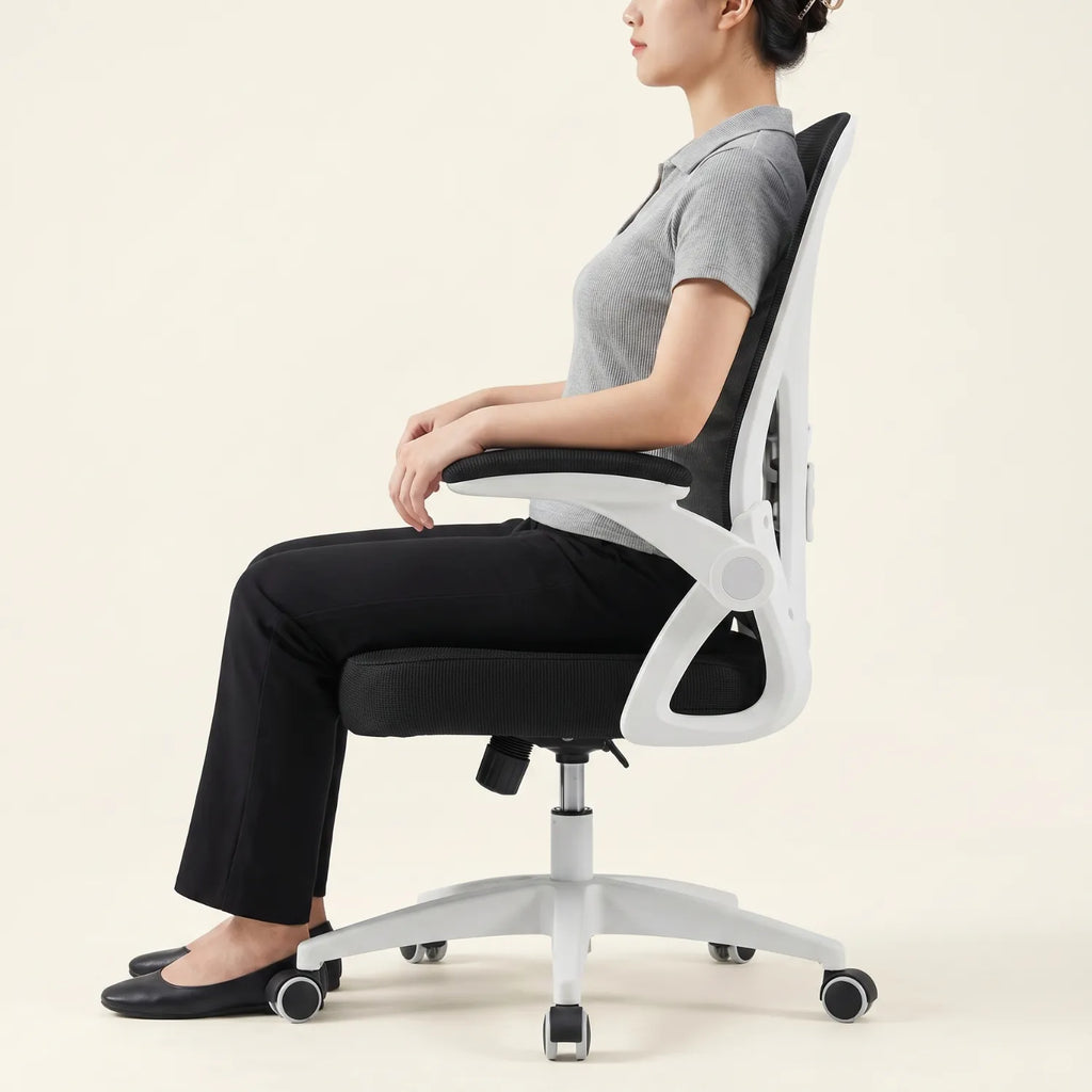 Femme assise de profil sur la chaise de bureau District 12 ergonomique mesh blanche et noire, posture droite soutien lombaire naturel, fond neutre