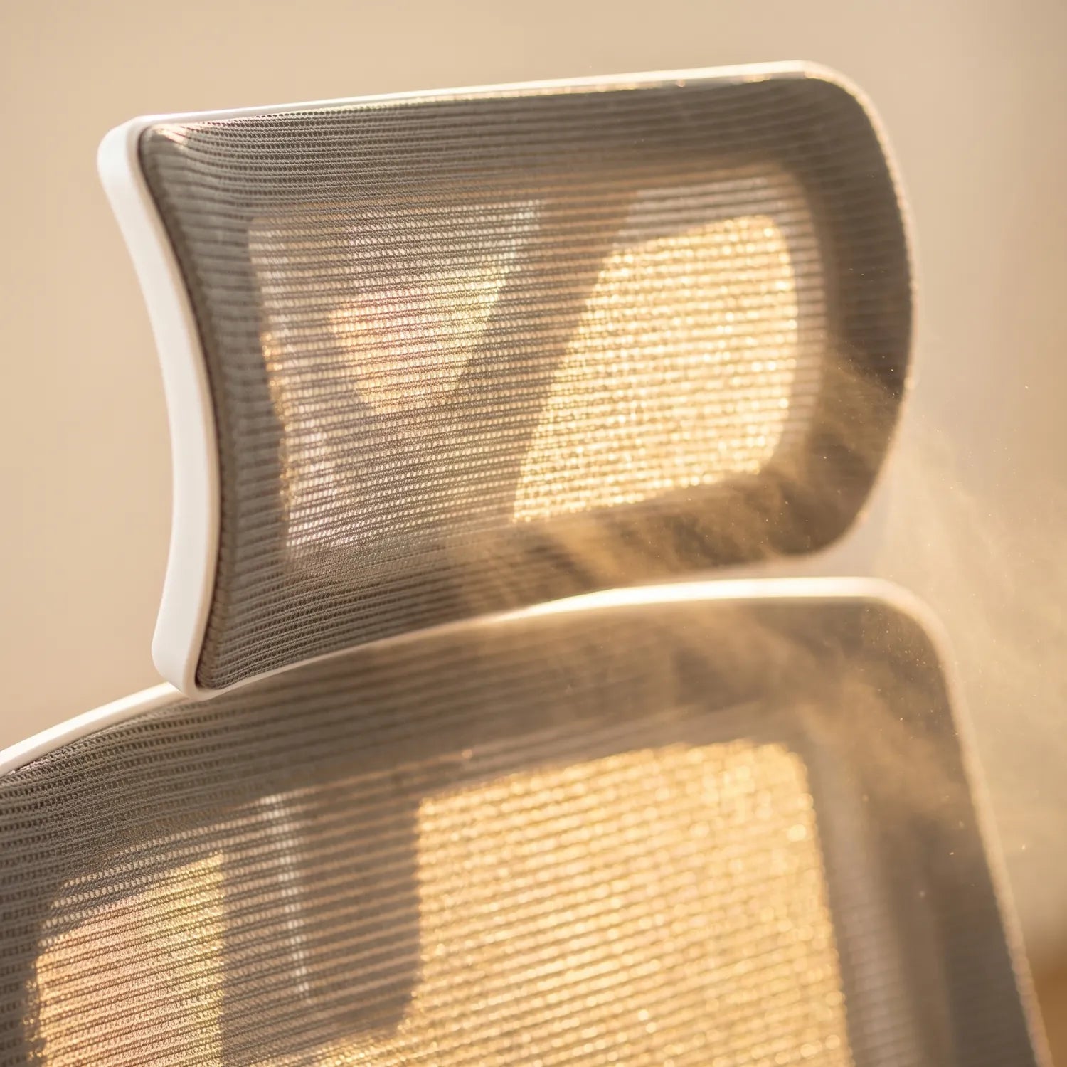 Gros plan appui-tête en maille respirante de la District 17 chaise de bureau ergonomique grise, texture filet aéré et cadre blanc lumière ambrée dorée