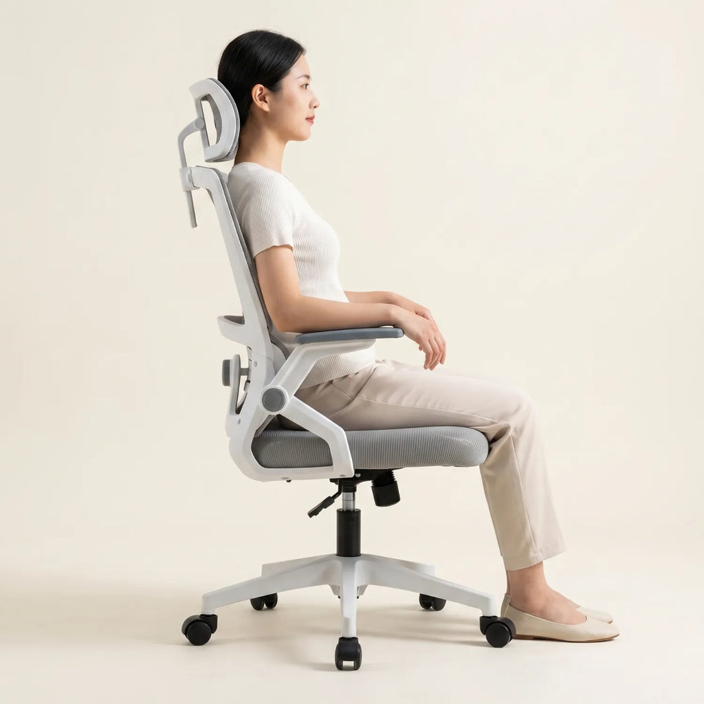 Femme assise de profil en posture ergonomique correcte sur la District 17 chaise bureau maille respirante appui-tête réglable, fond neutre studio crème