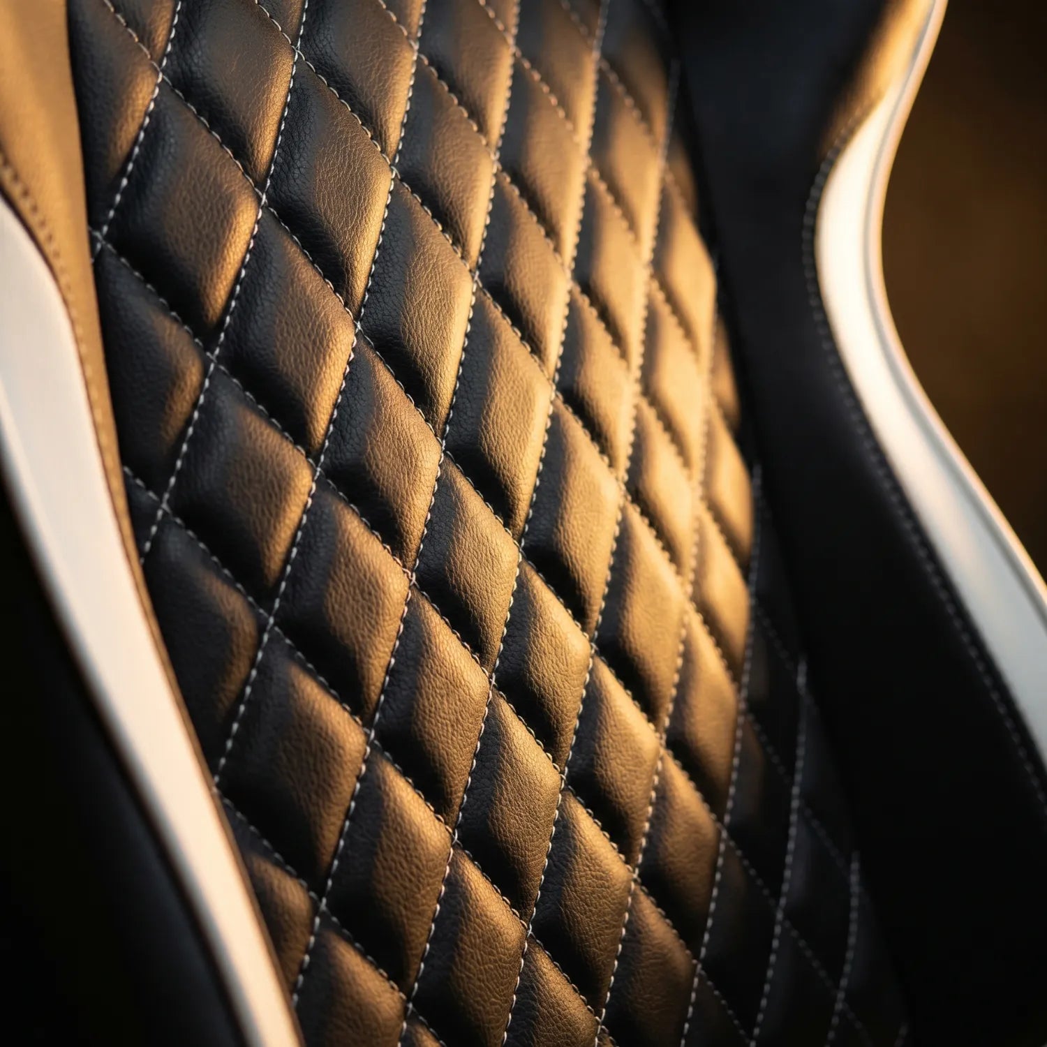 Gros plan capitonnage losanges cuir noir et blanc premium de la District 21 chaise gaming avec massage lombaire, piqûres contrastées finition racing luxueuse
