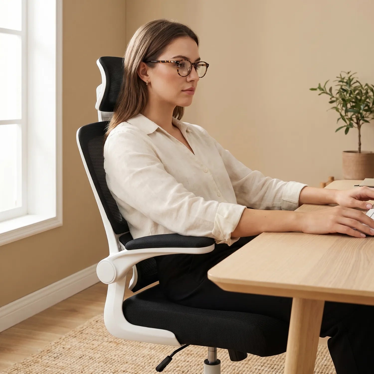 Femme avec lunettes assise de profil en posture ergonomique sur la District 22 chaise bureau maille 3 segments noir et blanc, bureau bois lumière naturelle home office beige