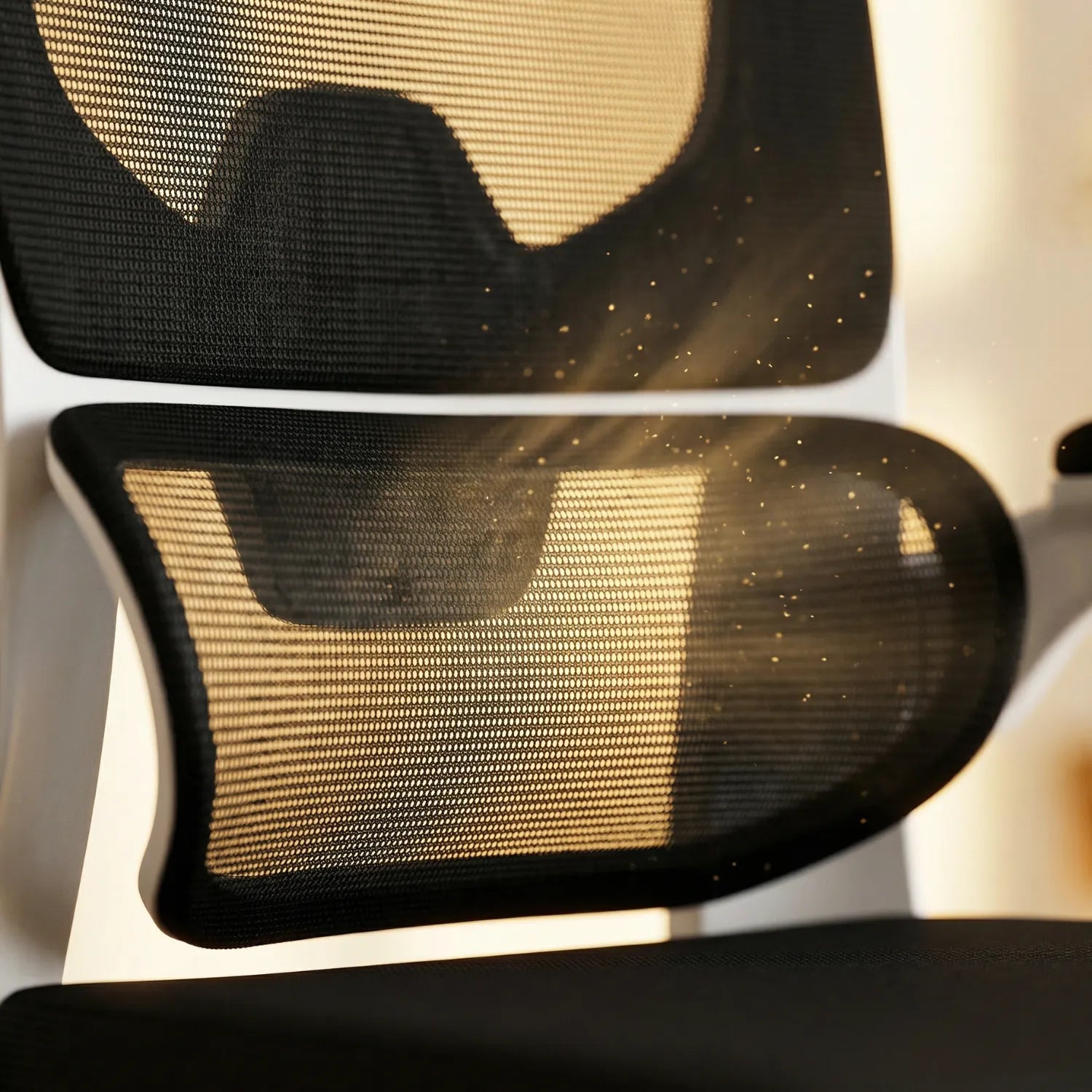 Gros plan soutien lombaire 3 segments maille noire de la District 22 chaise ergonomique cadre blanc, texture respirante aérée lumière ambrée confort longue durée